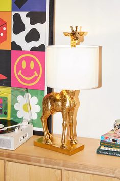 a gold horse lamp sitting on top of a wooden dresser next to a colorful wall