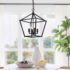 a dining room table with white chairs and a black chandelier hanging from the ceiling