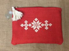 a red bag with white snowflakes on it and a tassel hanging from the handle