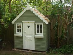 a small green shed with a white door and window on the side, next to a fence