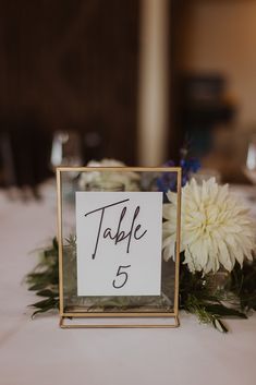 the table numbers are displayed in a gold frame on top of a white table cloth