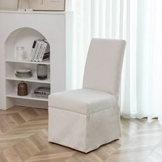 a white chair sitting in front of a book shelf on top of a hard wood floor