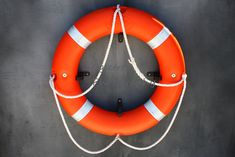 an orange life preserver hanging on the side of a building with ropes attached to it