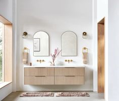 a bathroom with two sinks and mirrors on the wall next to a rug in front of it