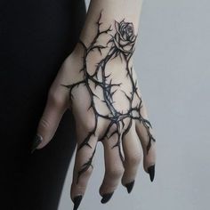 a woman's hand with branches and a rose tattoo on it