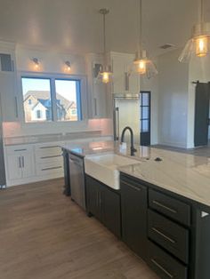 a large kitchen with an island in the middle and two sinks on each side, surrounded by white cabinets