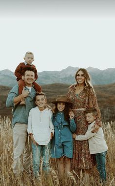 a family standing in tall grass with mountains in the background