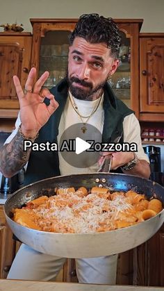 a man holding a large pan full of food in his hand and making the peace sign