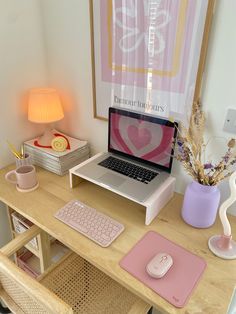 a laptop computer sitting on top of a wooden desk next to a pink mouse pad