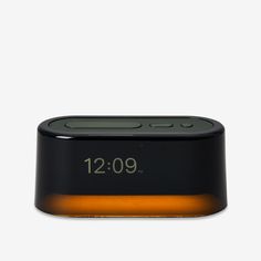 an alarm clock sitting on top of a white table next to a black and orange light