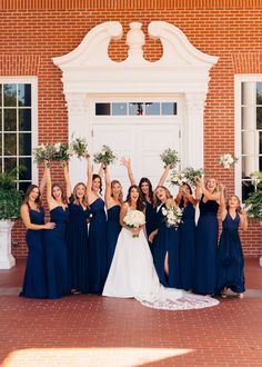 a bride and her bridal party posing for a photo in front of a brick building