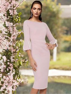 a woman in a pink dress standing next to a tree with flowers growing on it