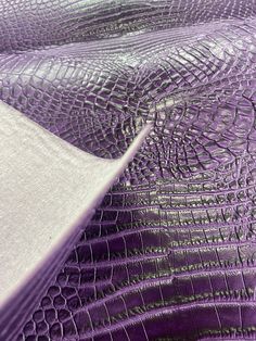 an up close view of the purple crocod leather material that has been used as a bed cover