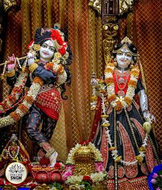 two statues of hindu deities in front of a mirror with flowers and decorations around them