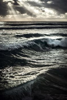 the sun is shining through clouds over the ocean