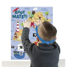 a young boy is looking at a book with an image of a pirate ship on it