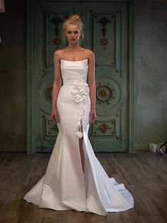 a woman in a white wedding dress standing on a wooden floor next to a door