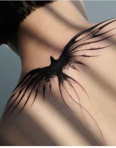 the back of a woman's shoulder with a bird tattoo on it