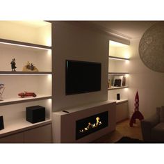 a modern living room with built in shelves and a flat screen tv