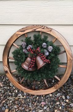 a christmas wreath with bells and pine cones in a wooden wheel on the side of a house