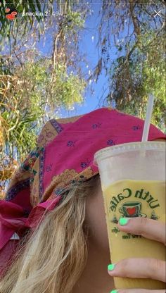 a woman holding up a drink in front of her face