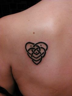 the back of a woman's shoulder with a heart tattoo on her left side