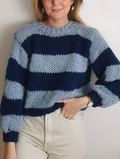 a woman is wearing a blue and white striped sweater with her hands on her hips