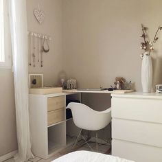 a bedroom with a white bed, desk and chair next to a window in the corner