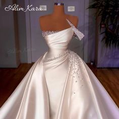 a white wedding dress with an off the shoulder neckline and beading on it