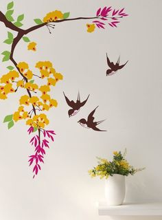 the birds are flying around the tree branch with yellow flowers and green leaves on it