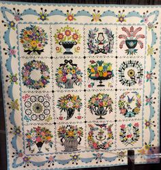 a quilt with flowers and vases on it