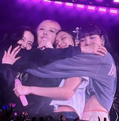 group of people hugging each other on stage with purple lights in the backround