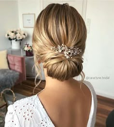 a woman with blonde hair in a low bun and a flowered headpiece is seen from the back