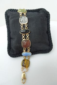 For sale: (1) s936 14k Yellow Gold Craved Multi Color Gemstone Scarab Bracelet 24.2g 7.75"   PLEASE READ ENTIRE DESCRIPTION BEFORE PURCHASING   Pre-owned item. Good condition. Please see pictures for details. Sold as is, as seen on pictures.We always test all metals, no matter if stamped or not. Perfect for daily wear. Would be a nice anniversary, birthday, Christmas, Mother's Day or Valentine's Day gift for her. This piece has a classic 60s vibe. Eight carved gemstone scarabs set in 14 karat yellow gold bezels. It would be lovely as part of a stack but is substantial enough on its own as well!  The scarabs all test as authentic gemstones, possibly Chrysoprase, Tiger's eye, Carnelian, Quartz, Blue Chalcedony and Jade The Scarab is the Egyptian symbol for eternal life. Specifications : Meta Formal Yellow Gold Bracelets With Stones, Gold Cabochon Gemstones For Formal Occasions, Formal Yellow Gold Bracelets With Natural Stones, Formal Gold Cabochon Gemstones, Antique Multi-stone Bracelet For Formal Occasions, Antique Multi-stone Bracelets For Formal Occasions, Collectible Gold Jewelry With Gemstone Accents, Formal Gold Bracelets With Gemstone Accents, Formal Gold Bracelets With Natural Stones