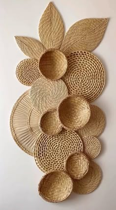 woven baskets are arranged in the shape of an abstract flower on a white wall with leaves