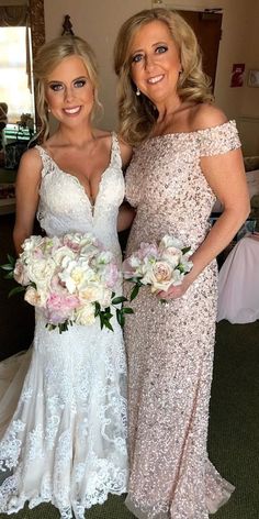 two beautiful women standing next to each other in front of a mirror holding bouquets