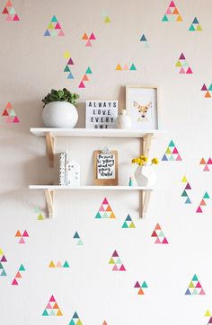 the wall is decorated with colorful triangle decals and shelving units, along with bookshelves