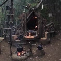 an outdoor kitchen made out of logs in the middle of the woods with candles lit inside