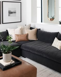 a living room with black couches and various pillows on the floor, along with a large mirror