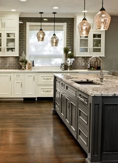 a large kitchen with white cabinets and marble counter tops