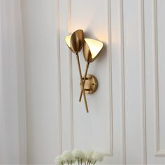 a wall light that is on the side of a white door next to a vase with flowers