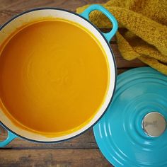 there is a pot of soup on the table next to a blue plate and yellow towel