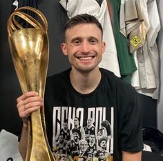 a man holding up a golden soccer trophy