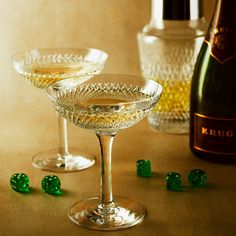 two wine glasses with green dices next to a bottle and glassware on a table