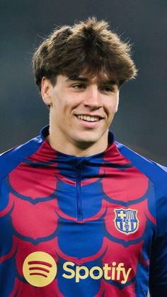 a young man in a soccer uniform smiles at the camera