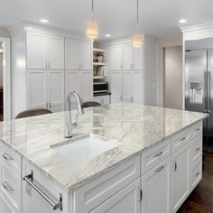 a large kitchen with white cabinets and marble counter tops, along with stainless steel appliances