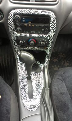 the interior of a car with black and white patterned dash cloth, steering wheel controls, and dashboard