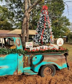 an old blue truck with a christmas tree in the back