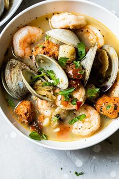 a white bowl filled with seafood and clams on top of a gray countertop