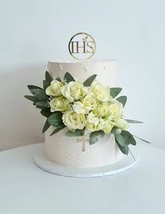 a wedding cake with white flowers and greenery on the top is decorated with a monogram